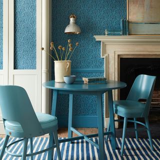 dining room with wallpaper, blue table and chairs, fireplace, rug