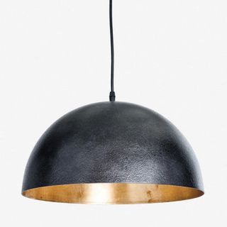 A large pendant light with a black exterior and brass interior 