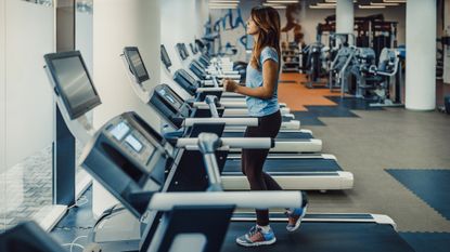 Woman walking on treadmill in empty gym