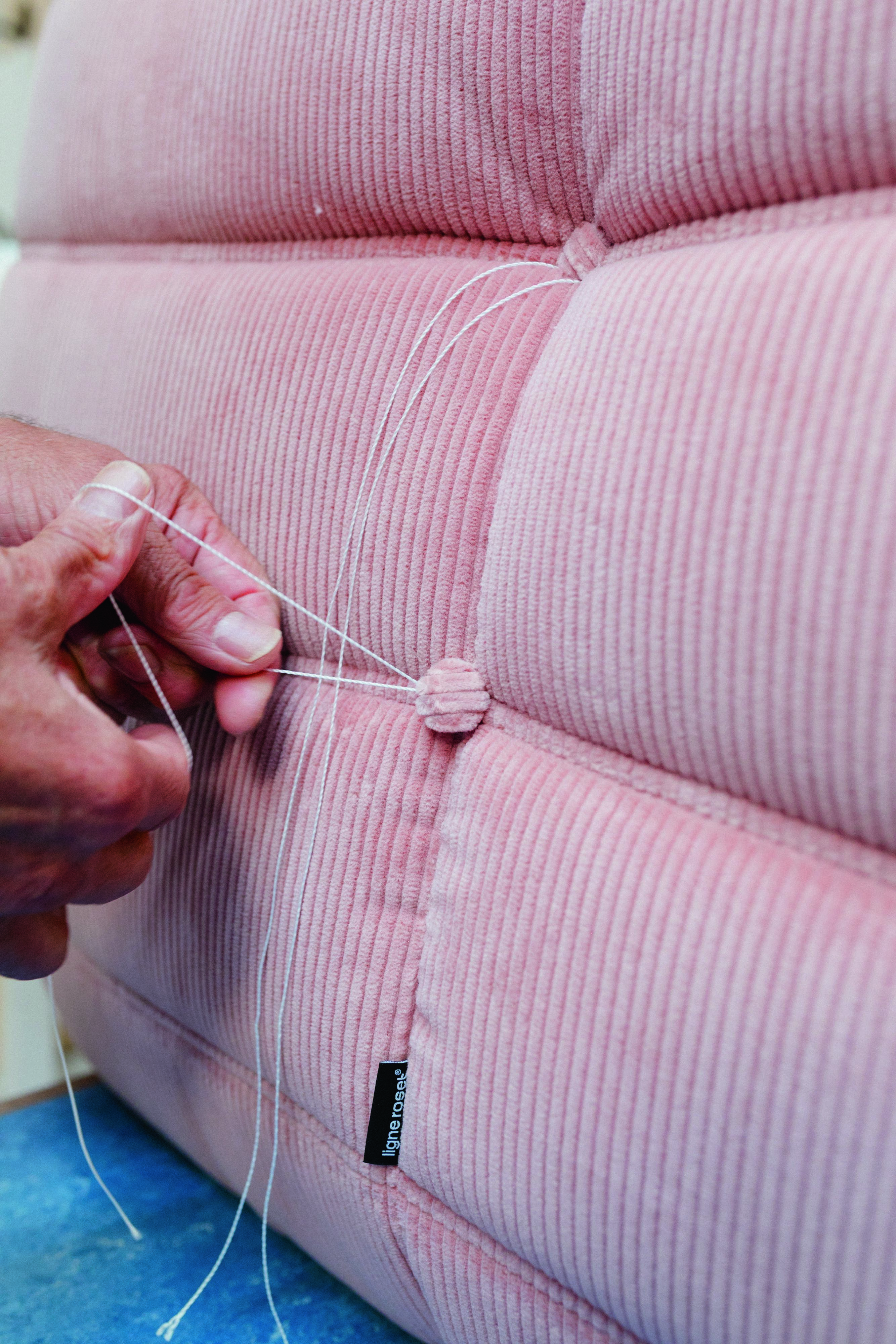 A master upholsterer hand-securing the Togo&amp;rsquo;s signature folds using blind tufting.
