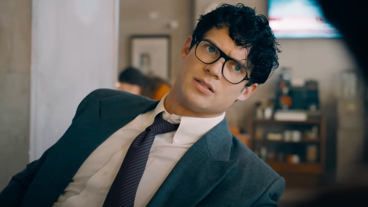 David Corenswet leans to his side in an office chair as he talks in Superman.