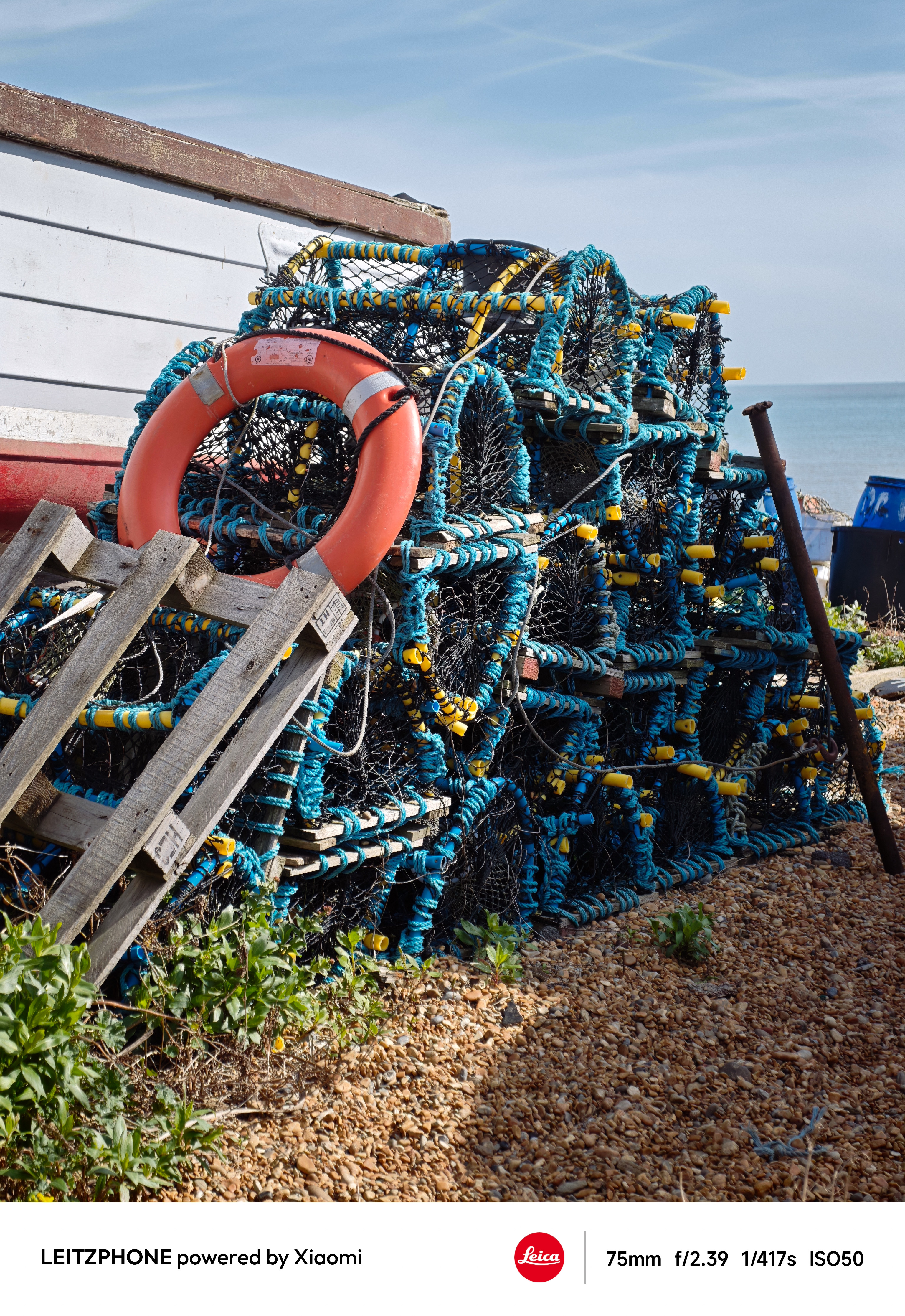 Color photo of stacked lobster pots with a bright orange lifebuoy