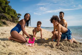 A family on the beach together laughing in the sunshine