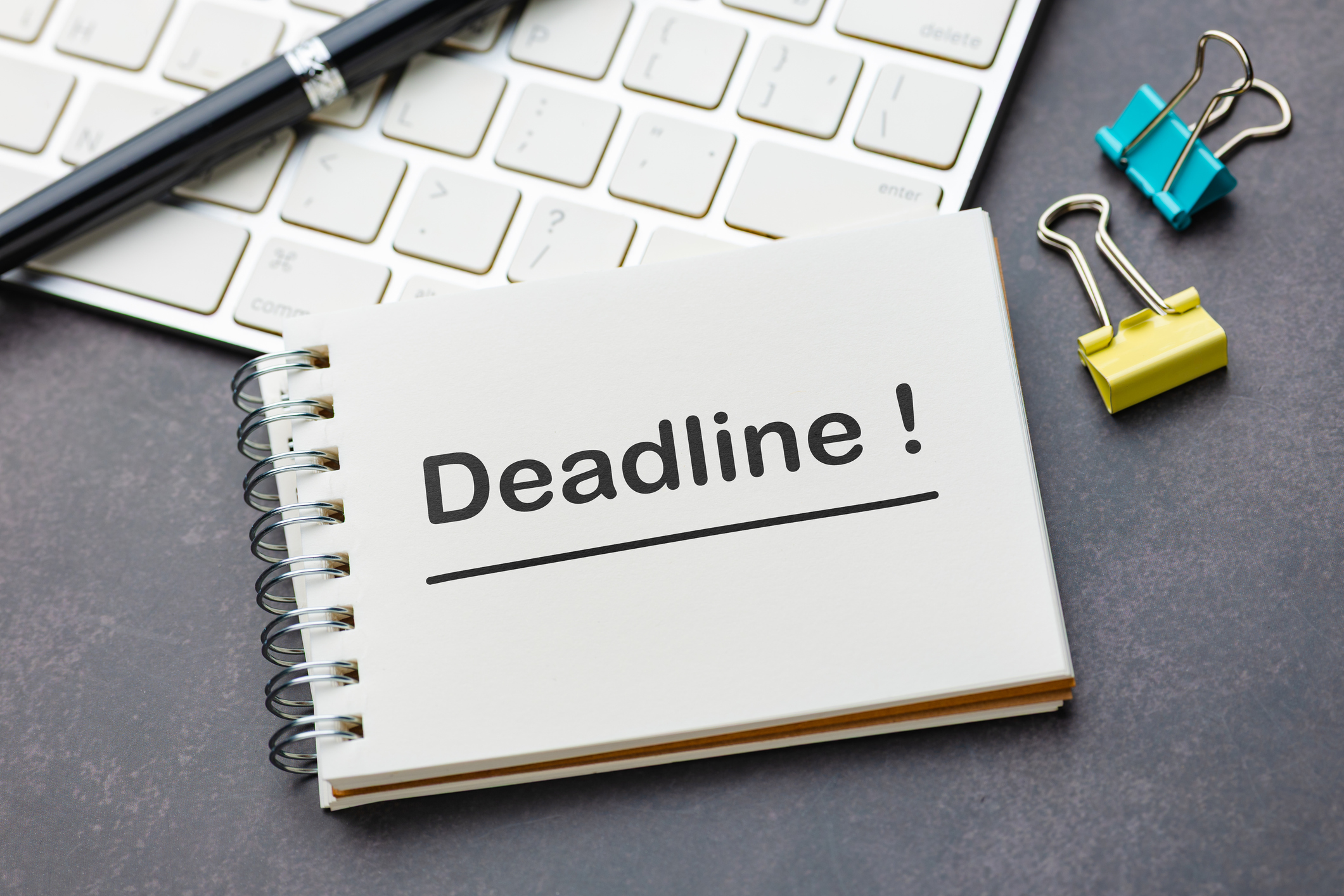 Conceptual image of deadline reminder showing a notebook with the word &amp;ldquo;Deadline!&amp;rdquo; placed on a desk with keyboard and office supplies