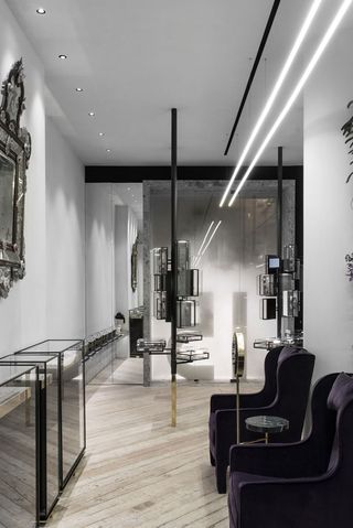 Shop interior of Greek Jewellery designer Ileana Makri with wooden floors, black cabinets, glass display cabinets and gold mirrors