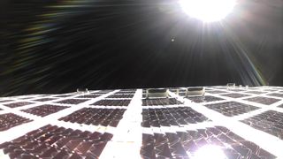 sun shines over solar panels with black of space in behind