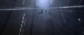 A screencap of an antagonist from the trailer. They’ve unleashed a web-like attack inside the opera house, and are suspended in the air with the webs surrounding them.
