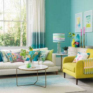 small living room with mint green walls, yellow chair and natural sofa