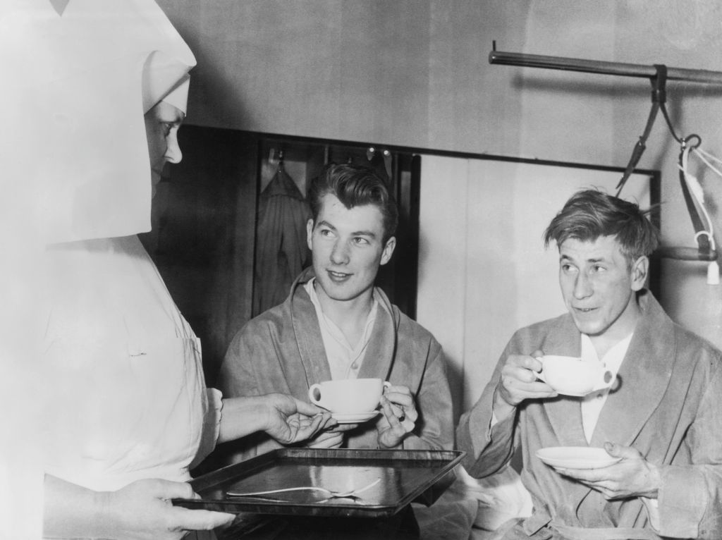 Manchester United players Ken Morgan, left, and Bobby Charlton receive hot soup from a nurse at the Isar Hospital in Munich where they are recovering from injuries sustained in the plane crash that killed 8 of their Busby Babes team mates, 11th February 1958