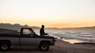 Man sitting on truck looking at ocean view