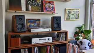 Sonus Faber Concertino G4 bookshelf speakers on a wooden stand, surrounded by turntable, amplifier and general audio equipment