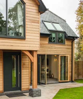 A timber clad self build with a slate roof and limestone patio to the front