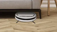 The iLife V3s Pro  robot vacuum fitting under a sofa to collect dust