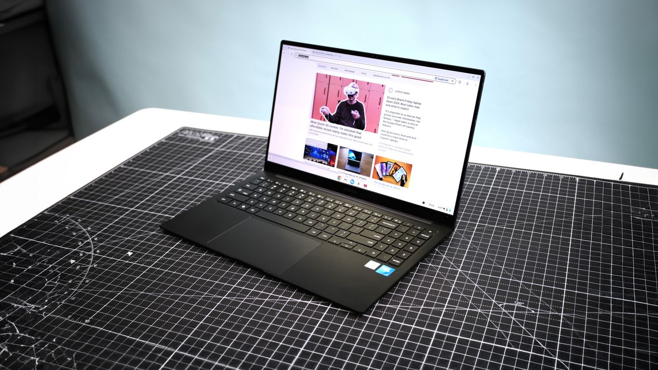 Samsung Galaxy Chromebook Plus open on a black cutting mat with the display showing Laptop Mag