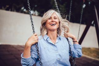 A woman laughs as she sits on a swing