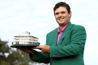 Patrick Reed wearing a green jacket holding a trophy
