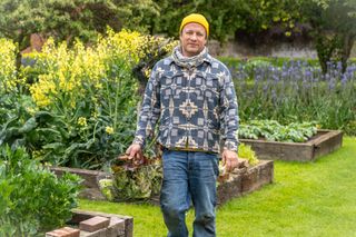 Jamie Oliver carrying a basket of lettuce that he's picked from his big garden.