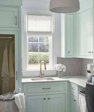 laundry room with light mint green cabinets