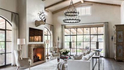 living room with fire lit and steel framed windows with vaulted ceiling