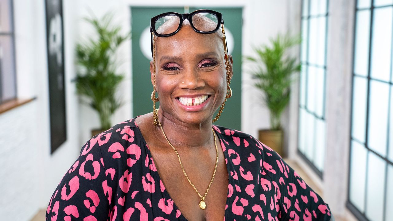 Andi Oliver smiling wearing a black and pink leopard print dress