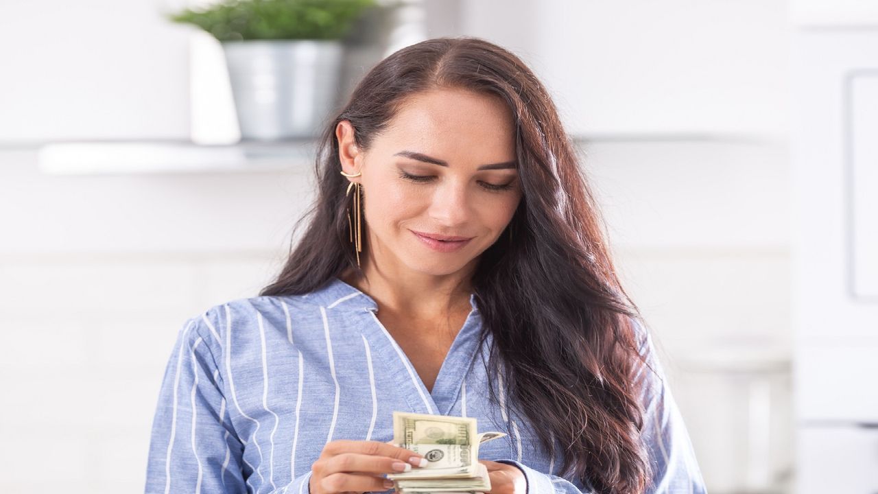 A woman holds a pile of cash.