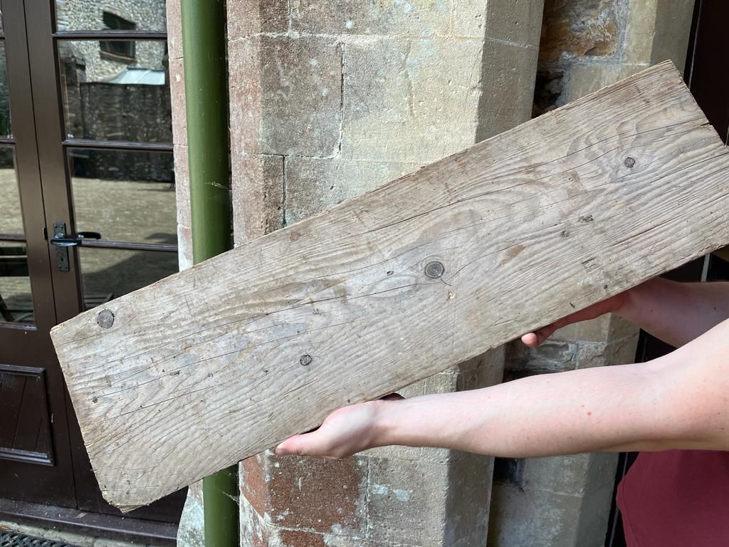A man holding a piece of rustic scaffold board