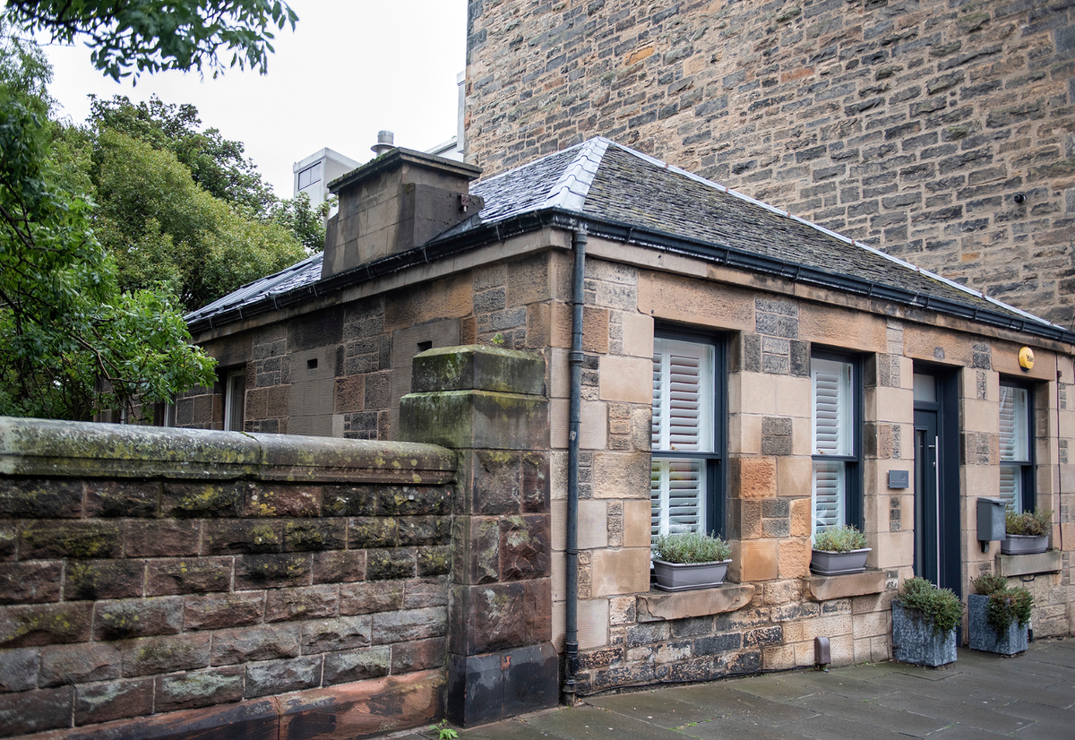 The Victorian house has stone walls, a pvc door and a stone wall connecting to the house