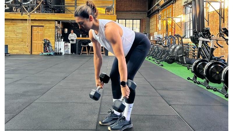 Jess performing a dumbbell deadlift with bent knees and dumbbells lowered down