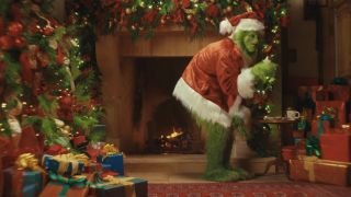 The Grinch eating cookies in front of a fireplace and Christmas decorations in The Grinch Ghoul Log