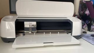 The best vinyl cutter machines; a Cricut Maker is on a table with the lid open