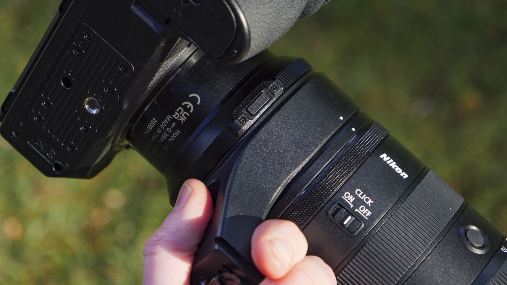 A hand holding Nikon Z 70-200mm f/2.8 VR S II lens by its tripod collar 
