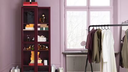 Dark painted IKEA cabinet in a pink bedroom with clothing rail