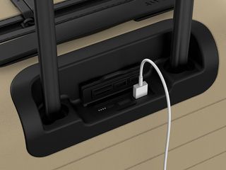 A close-up of a USB port and connecting wire at the top of the suitcase when the handle fits into.