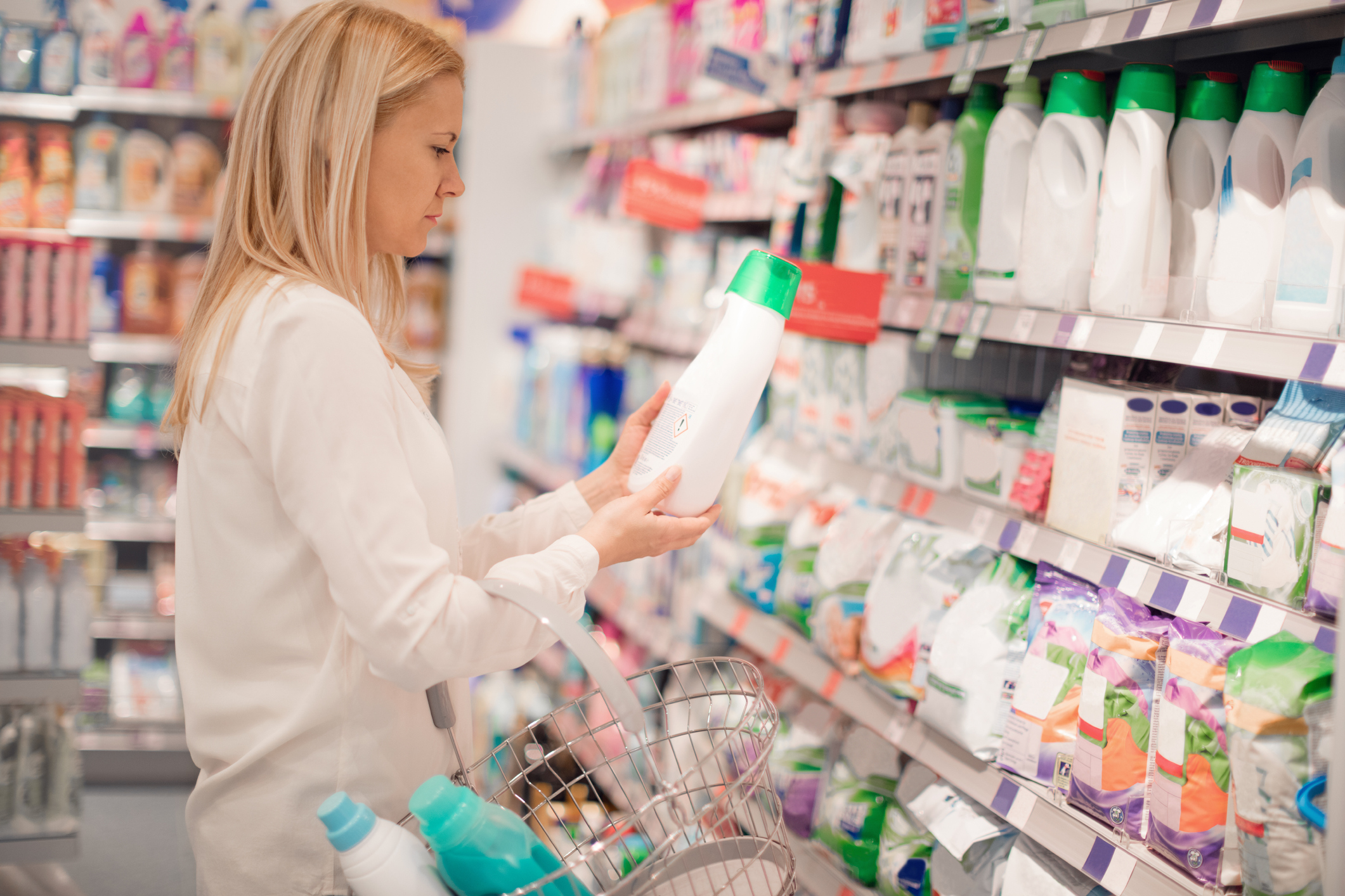 A woman is looking a the choice of laundry detergents on the supermarket shelves.