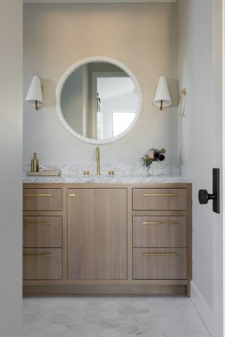 Bathroom with warm white walls, wood cabinet, white marble countertop and white accessories
