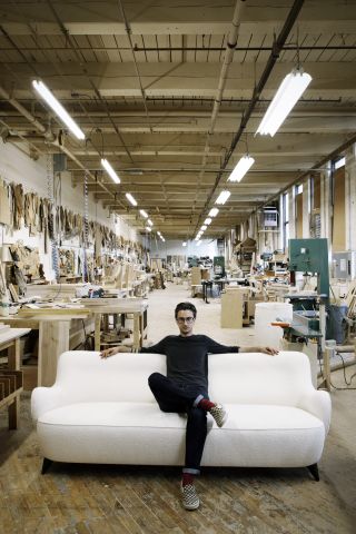 Chris Eitel posing on the ‘Barrel’ sofa in the furniture workshop