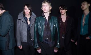 Group of male models in dark outerwear standing in studio