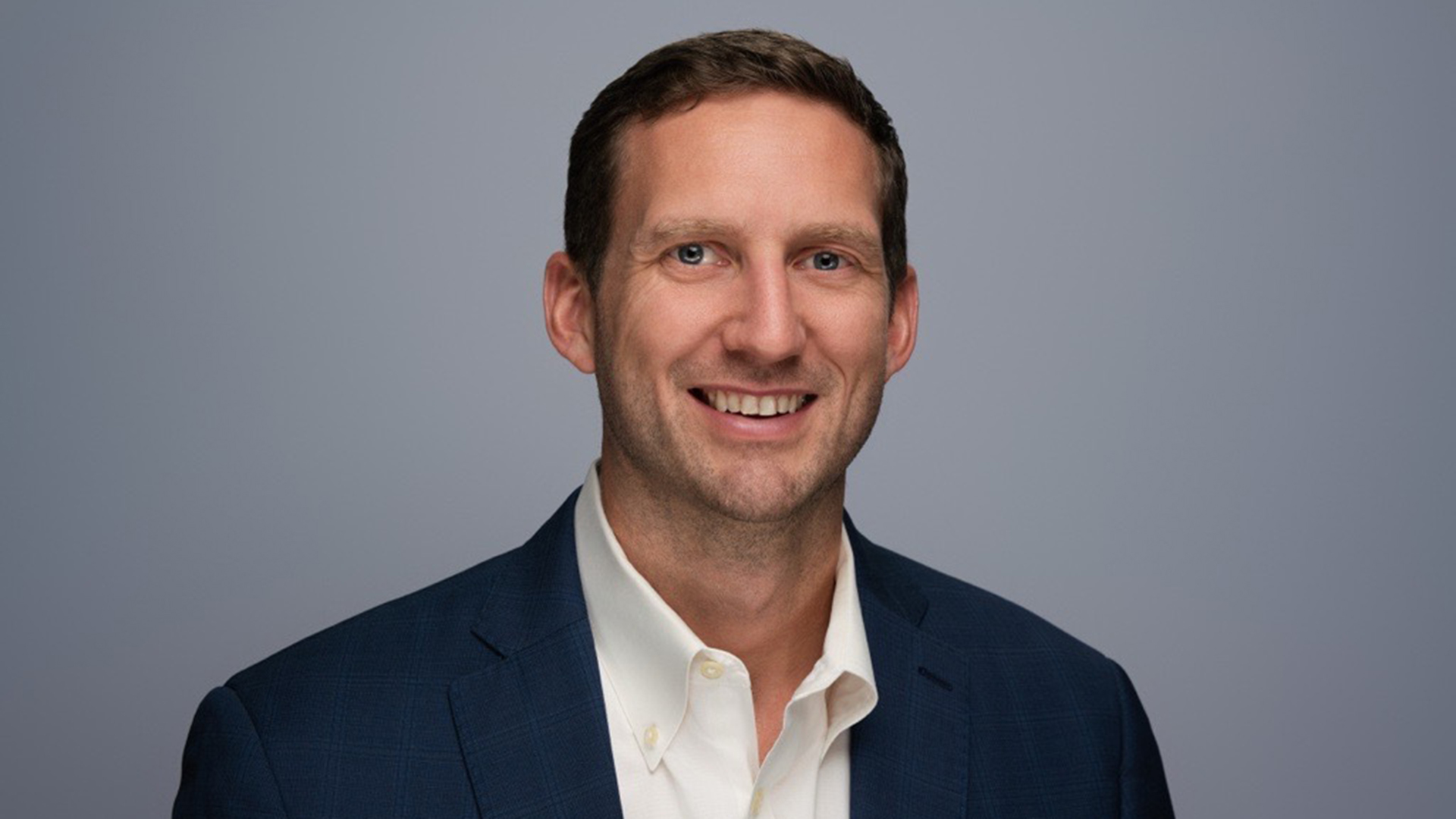 A headshot of Joel Hron, CTO at Thomson Reuters, stood against a grey background.