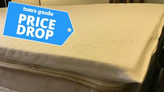 The Naturepedic Adagio Organic Latex Mattress Topper on a mattress with a deals badge in the top left-hand corner.