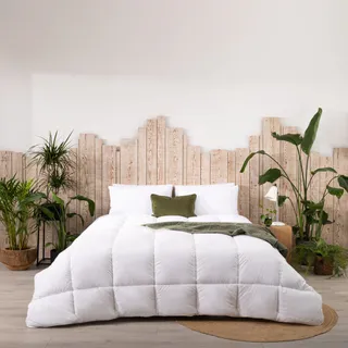 One of The Fine Bedding Company's duvet is styled on a double bed with moss-green pillows and throws, and plenty of plants surrounding the bedframe.