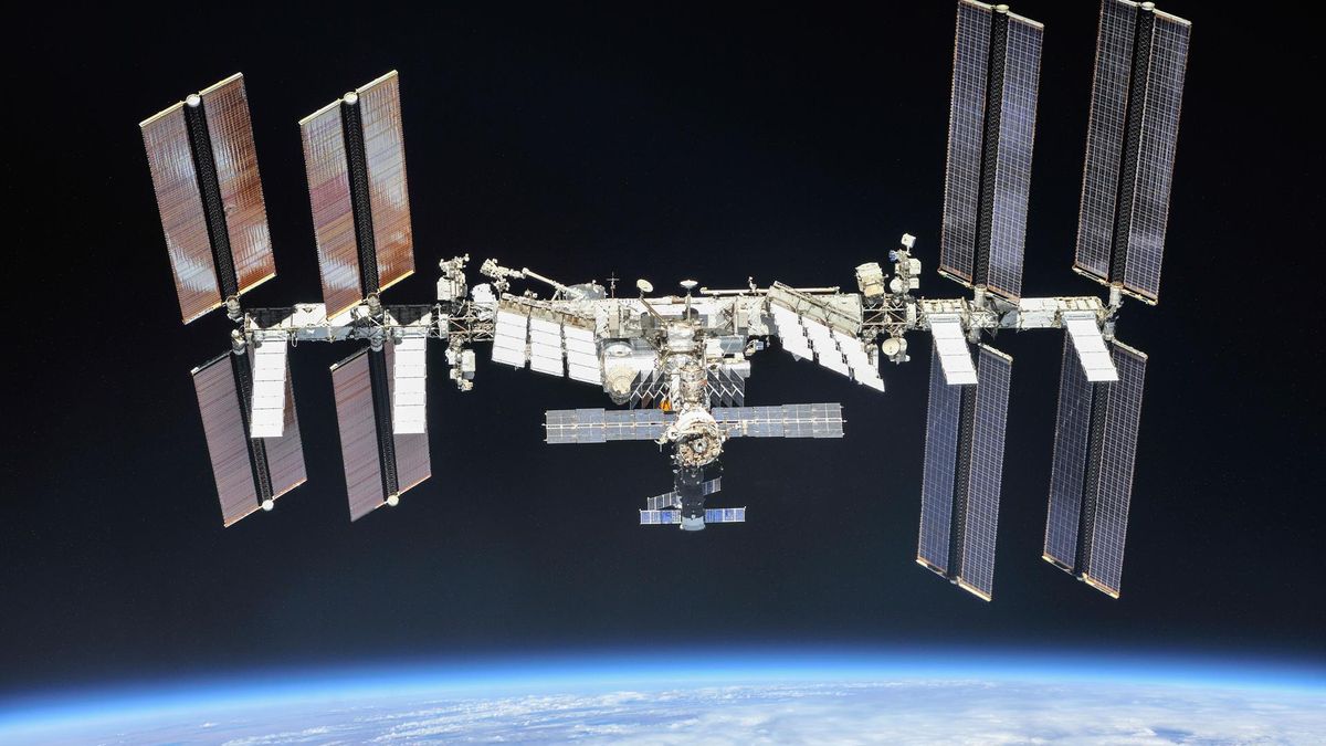 closeup photo of the international space station, with the curve of earth in the background