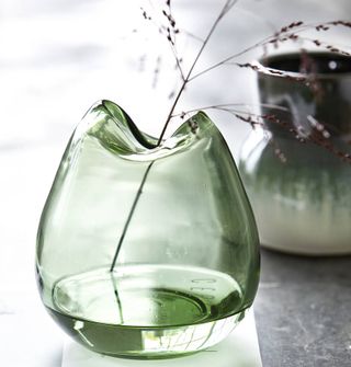 Not On The High Street Wave Vase made from green tinted glass on a grey surface