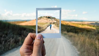 Looking through a picture frame at a boy walking down a road in the distance.