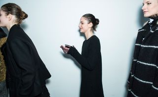 three female models walking past the camera wearing black clothing