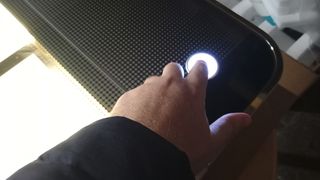 Glowforge Pro review, a man's hand pushes a large glowing button on a laser cutter