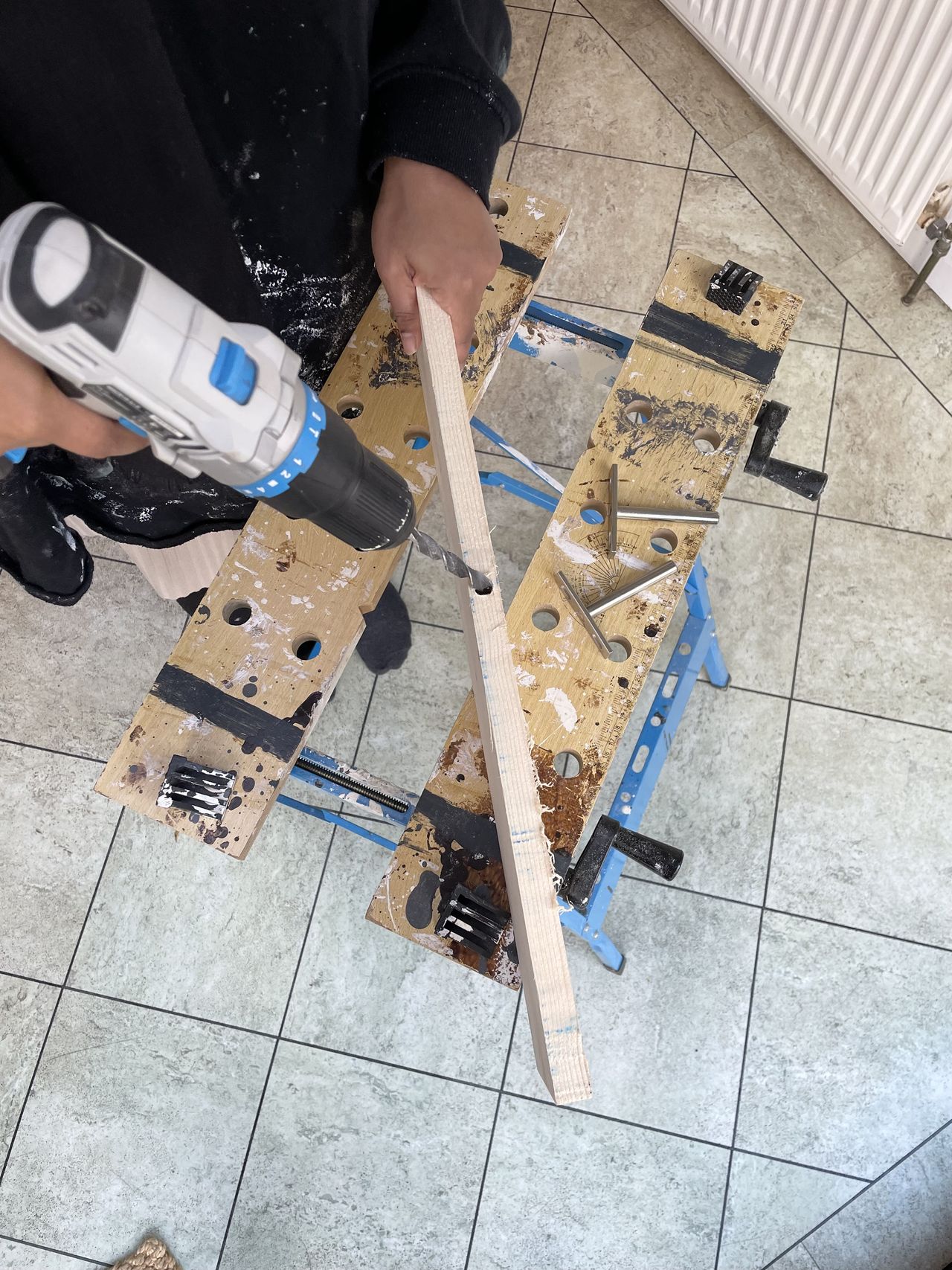 A woman drills holes into the back of a wooden shelf