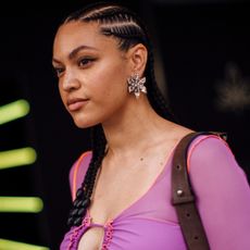Fashion week attendee at london spring 2024 wearing purple top, braids, and winged eyeliner