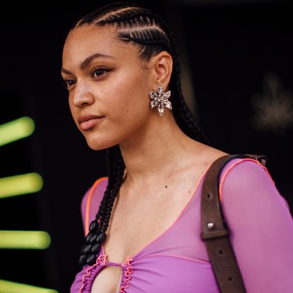 Fashion week attendee at london spring 2024 wearing purple top, braids, and winged eyeliner
