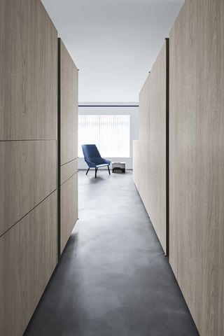 Interior of Alex's apartment in Singapore with wood cubicles, grey floor and blue chair