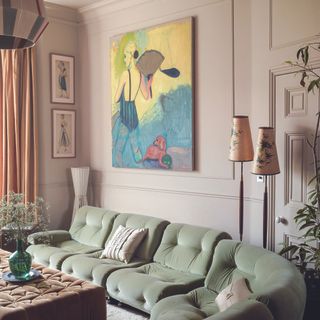 Pink living room with art on wall and green sofa